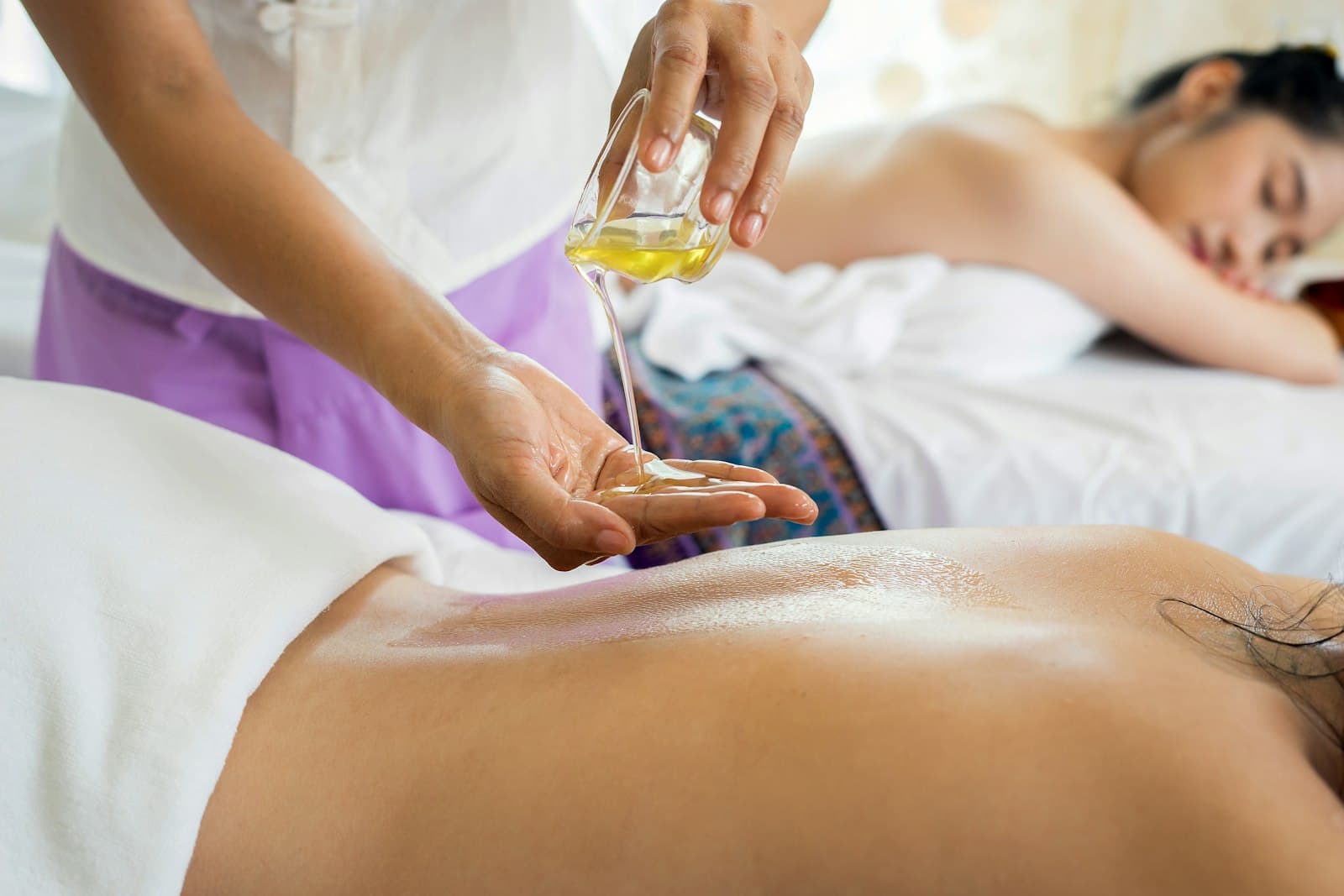 Spa therapist pouring massage oil during a treatment session